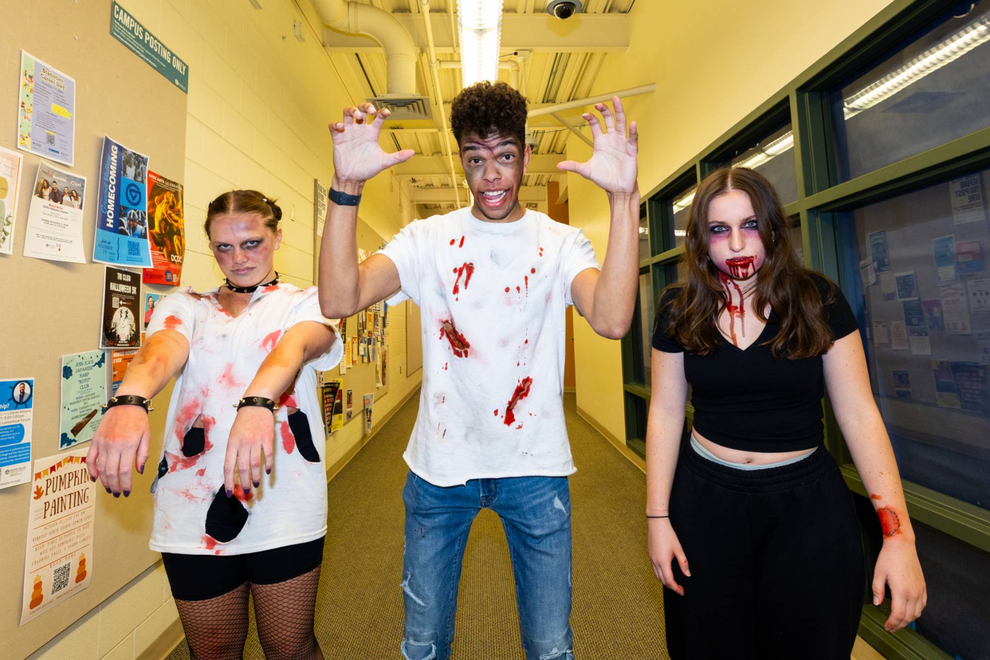 three students stand in a hallway dressed up as zombies